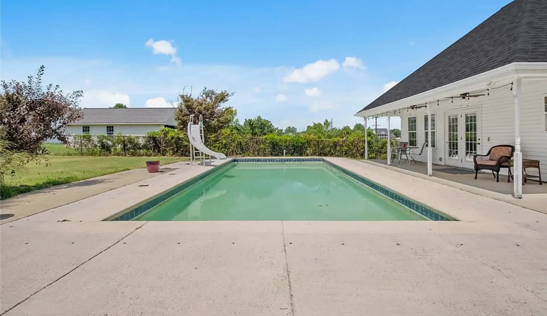 Plain cracked concrete pool deck with stains before resurfacing