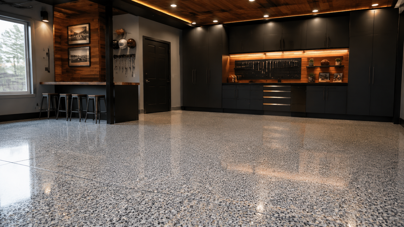 Polished flake epoxy garage floor in a finished Northwest Arkansas garage with black cabinetry and workbench