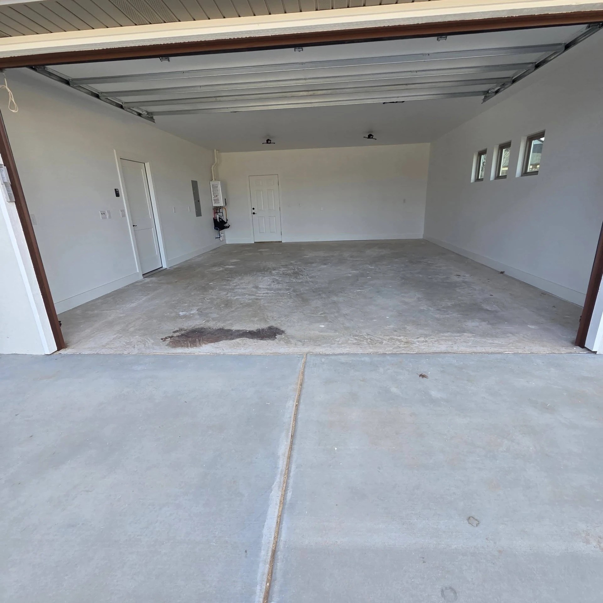 Bare stained concrete garage floor with an oil spot before epoxy was applied